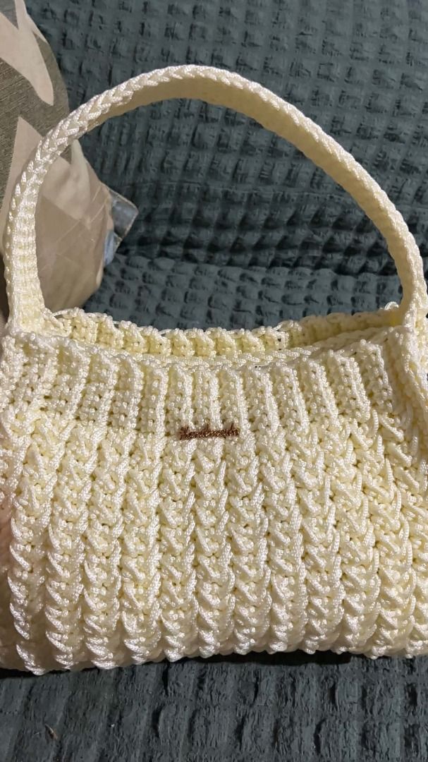 Cream Crochet Shoulder Bag with Handle (Category: Shoulder Bags) located in Caloocan City. Submitted by jnksknotsandfuzzyflowers (Listing ID 1462458983, Image 1). Description: - Handmade crochet shoulder bag in a beautiful cream color. - Features a unique textured stitch pattern all over. - Sturdy, crocheted handle for comfortable carrying. - Adorned with a small metallic 'handmade' tag. - Ideal for casual outings and adding a unique touch to you