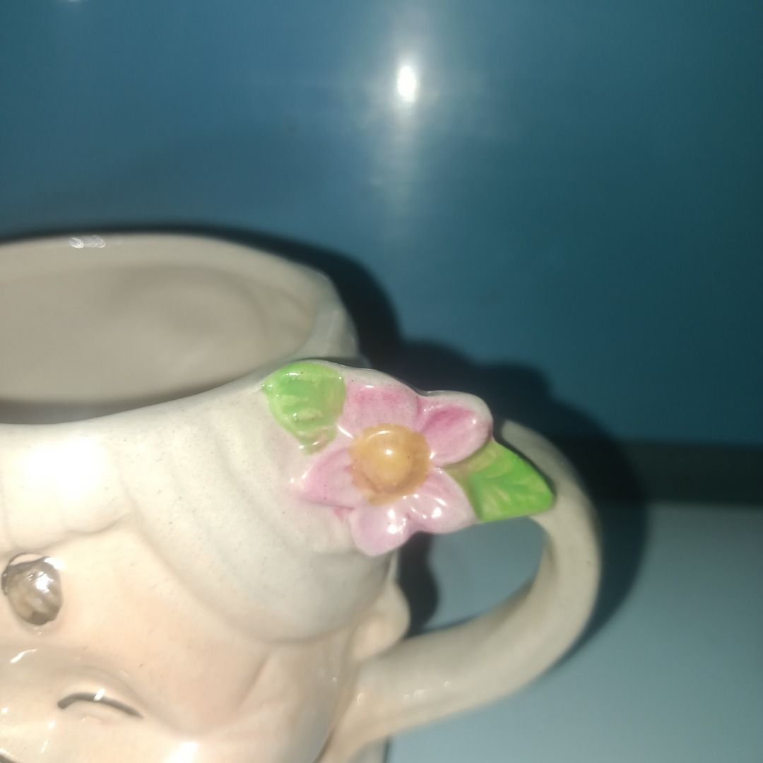 Cute Grandma Face Ceramic Mug (Category: Coffee & Tea Tableware) located in Munoz. Submitted by larryc1212 (Listing ID 1462490683, Image 2). Description: - Adorable ceramic mug shaped like a grandma's face - Features a smiling grandma with glasses and a flower in her hair - Simple loop handle - Pink base - Ideal for coffee or tea - Unique collectible item Disclaimer: Item may include some scratches due to age, as is were is basis Item can be pick
