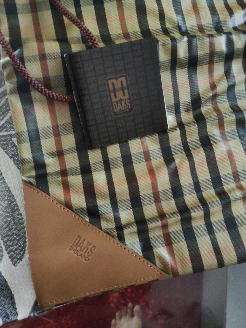 DAKS England Plaid Drawstring Pouch Bag with Box (Category: Purses & Pouches) located in Batangas. Submitted by ms.d_preloveditems (Listing ID 1462479449, Image 3). Description: - Authentic DAKS England plaid pouch - Features a classic drawstring closure - Elegant leather trim accents - Comes with original box and tag - Ideal for organizing essentials or as a travel companion - Lined interior in black - Offers a charming vintage aesthetic.