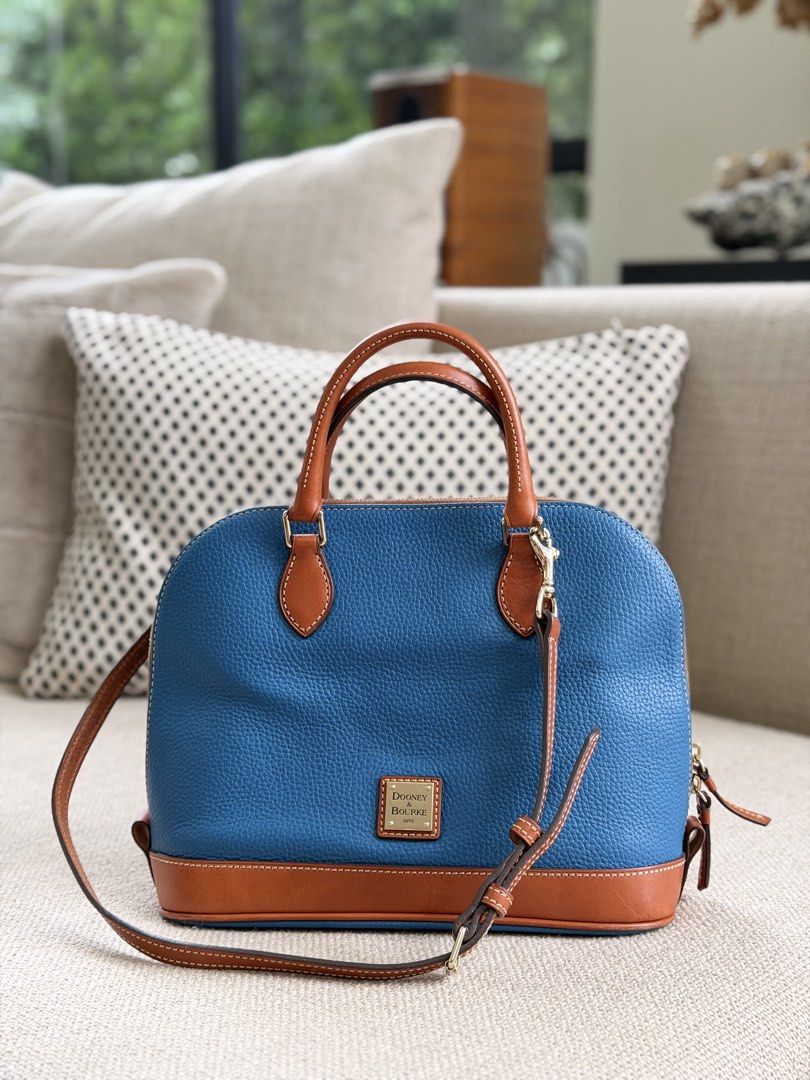 Dooney & Bourke Blue Leather Satchel Bag (Category: Luxury Bags & Wallets) located in Las Pinas. Submitted by cawyl (Listing ID 1462550050, Image 1). Description: - Stylish blue leather satchel bag - Contrasting tan leather trim - Comfortable top handles - Includes a detachable crossbody strap for versatile wear - Elegant gold hardware accents - Prominent logo on the front - Ample interior space for essentials - Ideal for everyday use.