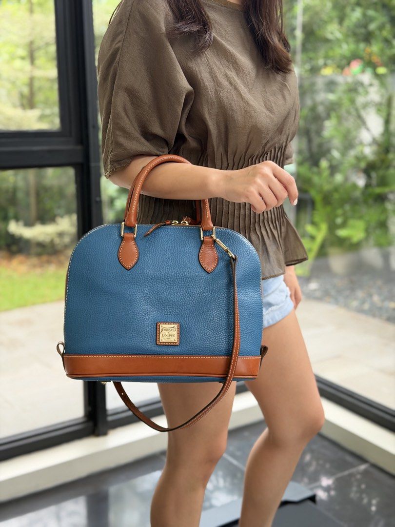 Dooney & Bourke Blue Leather Satchel Bag (Category: Luxury Bags & Wallets) located in Las Pinas. Submitted by cawyl (Listing ID 1462550050, Image 2). Description: - Stylish blue leather satchel bag - Contrasting tan leather trim - Comfortable top handles - Includes a detachable crossbody strap for versatile wear - Elegant gold hardware accents - Prominent logo on the front - Ample interior space for essentials - Ideal for everyday use.