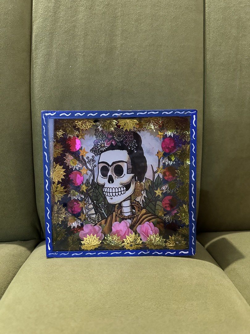 Frida Kahlo Shadow Box Art FROM MEXICO (Category: Art & Prints) located in Las Pinas. Submitted by petiteclothes_2000 (Listing ID 1462549577, Image 2). Description: - Handmade shadow box with a Frida Kahlo-inspired skeleton portrait. - Adorned with beautiful flowers, stars, and glittery accents. - Encased in a vibrant blue frame. - Ideal for unique home decor or as a thoughtful gift..