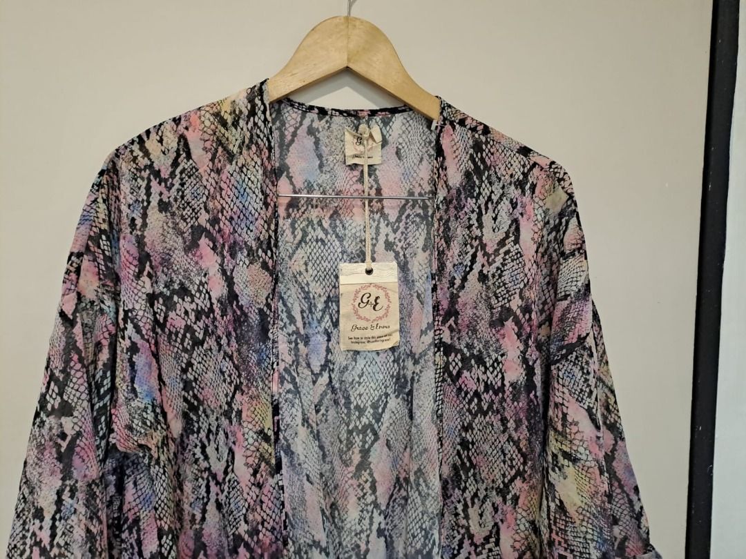Grace & Emma kimono or cover up (Category: Others Tops) located in Mandaluyong City. Submitted by epicowl-c93c (Listing ID 1462583381, Image 2). Description: The image displays a lightweight, open-front kimono-style cardigan or cover-up featuring a vibrant multi-colored snakeskin or python print pattern. The garment blends shades of pink, purple, lavender, and faint yellow accents contrasted by bold black and gray scales..