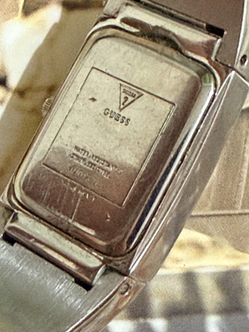 Guess women’s rectangular two-tone quartz watch. (Category: Women's Watches) located in Pasig City. Submitted by smartshopping.ph (Listing ID 1462455618, Image 3). Description: Guess women’s rectangular two-tone quartz watch. A sleek, rectangular stainless steel case framing a minimalist silver/white sunburst dial. It features simple gold-tone hour markers at the 12, 3, 6, and 9 o’clock positions with gold-tone hands. An integrated solid-link cuf