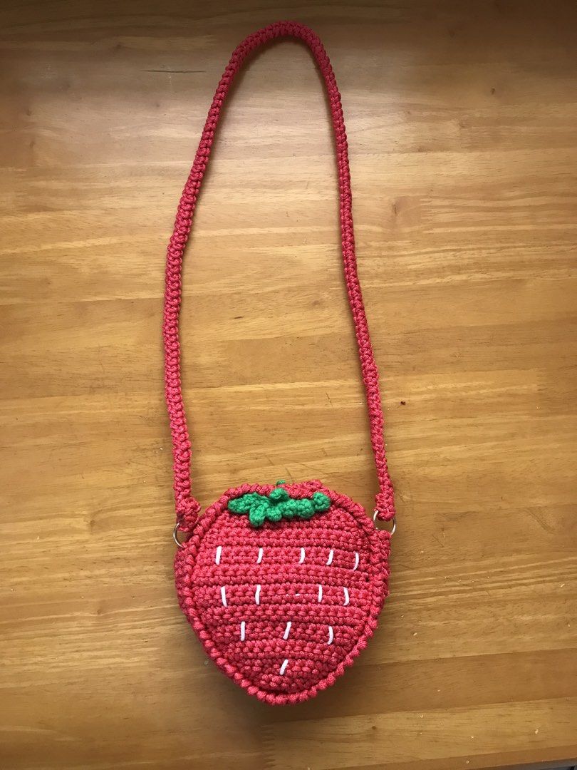 Handmade Strawberry Crocheted Bag with Strap (Category: Shoulder Bags) located in Imus. Submitted by mrsz3r0 (Listing ID 1462506104, Image 2). Description: - Adorable strawberry-shaped bag - Hand-crocheted craftsmanship - Features a braided strap - White stitching mimics strawberry seeds - Cute green leaf detail at the top - Includes a small 'Hook & Yarn St.' wooden tag - Ideal for children or as a playful accessory.