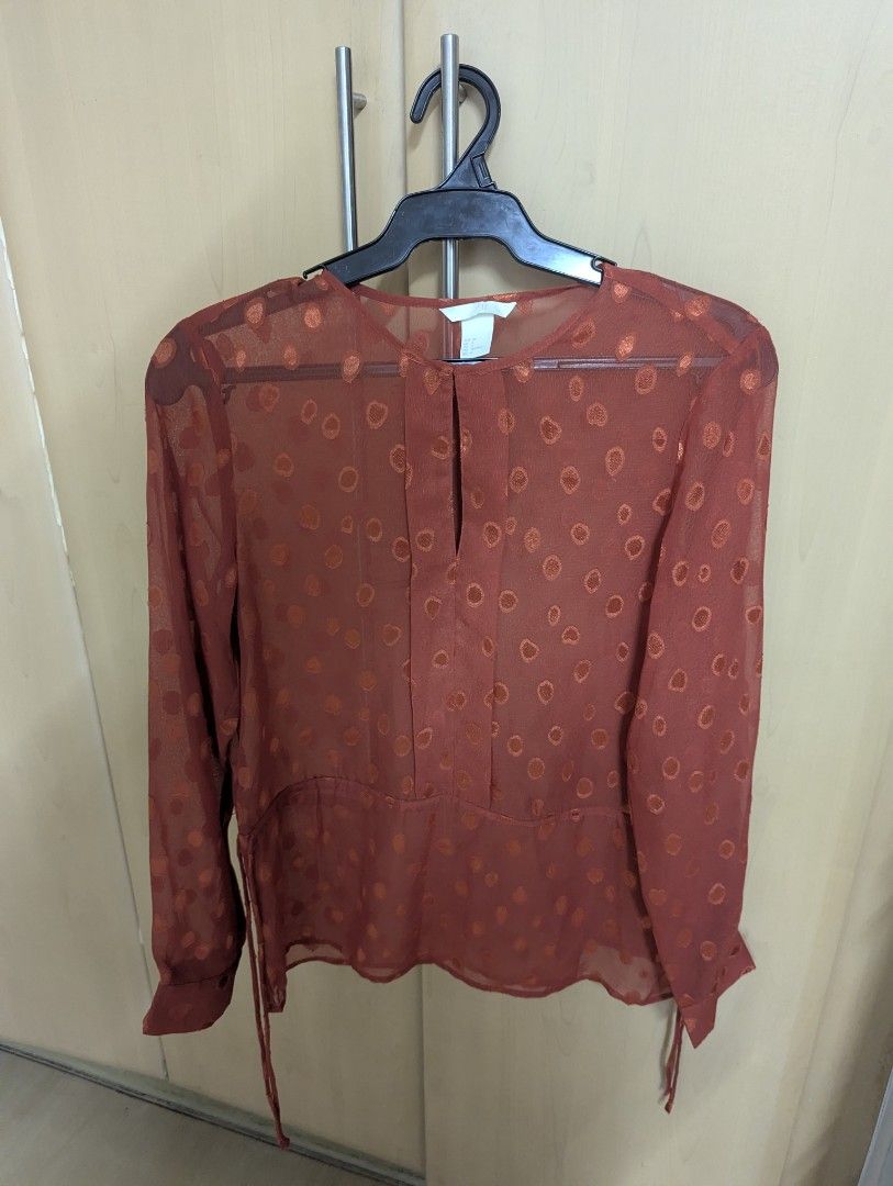 H&M Sheer Polka Dot Blouse (Category: Blouses) located in Taguig. Submitted by hlco13 (Listing ID 1462637808, Image 1). Description: - Sheer long-sleeved blouse from H&M - Beautiful reddish-orange color with a subtle polka dot pattern - Elegant keyhole detail at the neckline - Adjustable side ties for a customized fit - Made of 100% polyester - Versatile for layering or wearing solo.