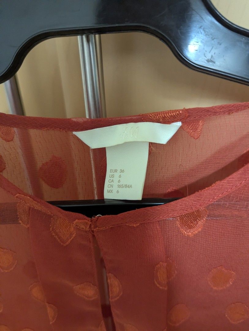 H&M Sheer Polka Dot Blouse (Category: Blouses) located in Taguig. Submitted by hlco13 (Listing ID 1462637808, Image 2). Description: - Sheer long-sleeved blouse from H&M - Beautiful reddish-orange color with a subtle polka dot pattern - Elegant keyhole detail at the neckline - Adjustable side ties for a customized fit - Made of 100% polyester - Versatile for layering or wearing solo.