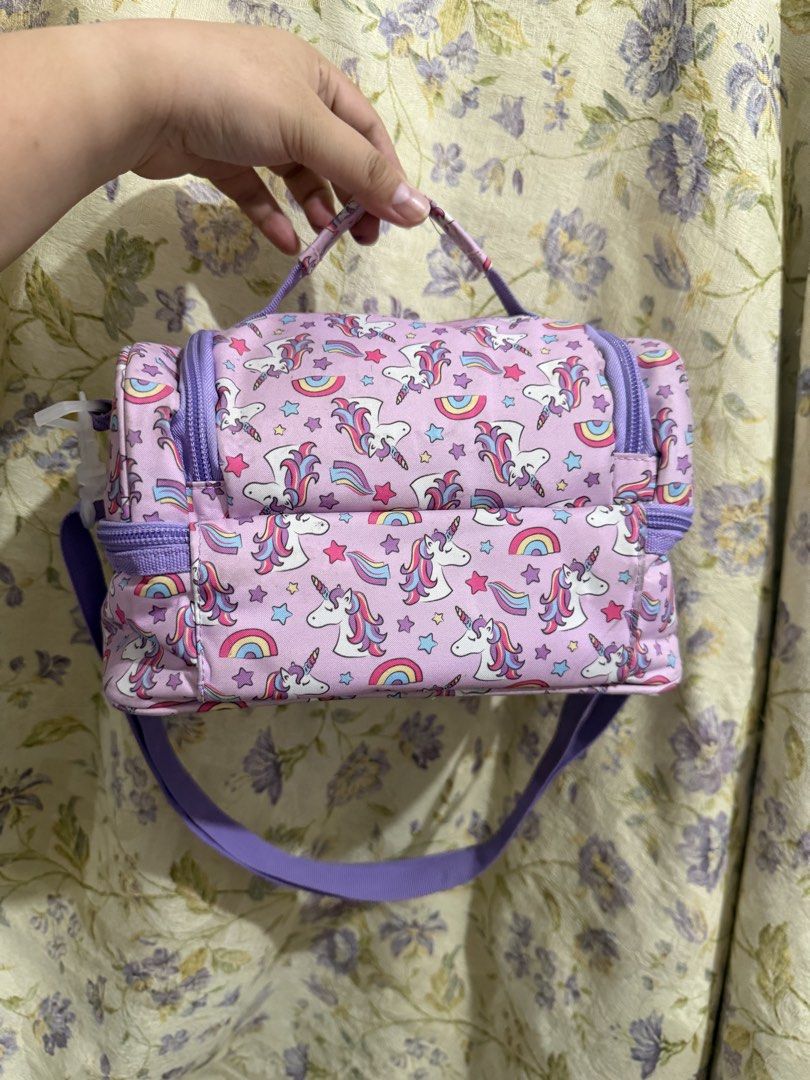 Kids Unicorn Rainbow Lunch Bag (Category: Babies & Kids Fashion) located in Binan City. Submitted by prelovedlagunaph (Listing ID 1462620206, Image 2). Description: - Adorable pink lunch bag featuring cute unicorns and rainbows. - Two spacious zippered compartments to keep food fresh. - Convenient top handle for easy carrying. - Includes a detachable shoulder strap for versatile wear. - Ideal for school lunches, day trips, or picnics. - Easy-to-c