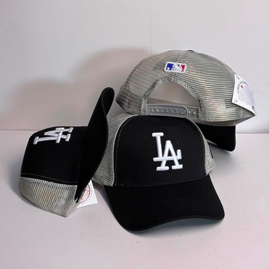 La Trucker cap (Category: Caps & Hats) located in Bacoor. Submitted by snapgame (Listing ID 1462521486, Image 1). Description: The image shows a black and grey mesh trucker baseball cap featuring the Los Angeles Dodgers (“LA”) embroidered logo on the front..