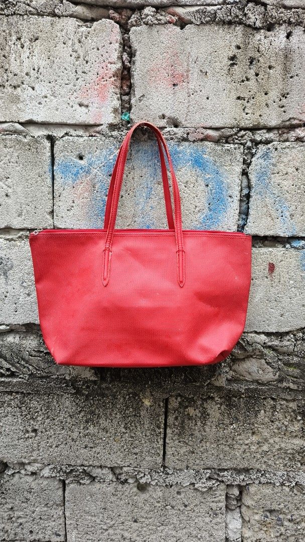 Lacoste Red Tote Bag (Category: Tote Bags) located in Paranaque City. Submitted by jtan1717838746 (Listing ID 1462500390, Image 2). Description: - Classic red Lacoste tote bag - Features the iconic crocodile logo - Interior zippered pocket for secure storage - Lined with repeating Lacoste logo - Spacious design, ideal for everyday essentials.