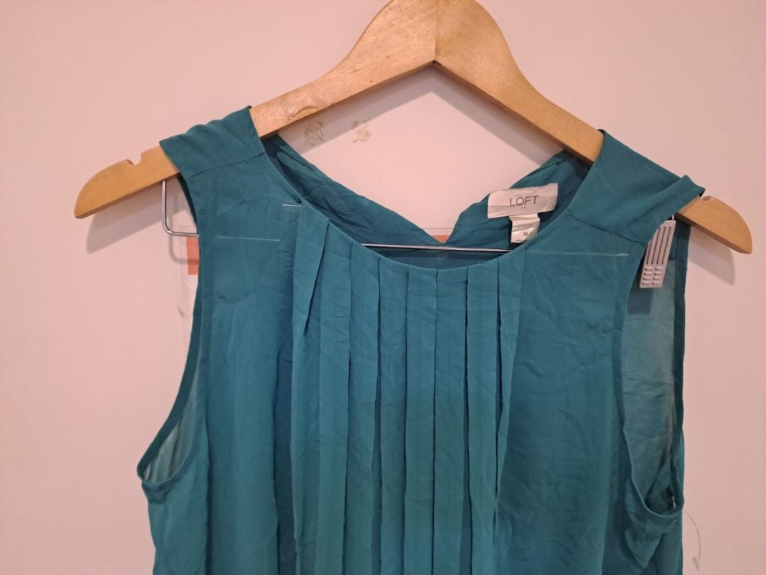 Loft by anne taylor olive green (Category: Sleeveless) located in Mandaluyong City. Submitted by epicowl-c93c (Listing ID 1462585793, Image 2). Description: This is a teal pleated sleeveless blouse from the popular retail brand LOFT (originally a division of Ann Taylor).The garment features a crew neckline with structured vertical accordion pleats flowing down the front bodice. It is made of a lightweight, flowy fabric—typically a polyester or ra