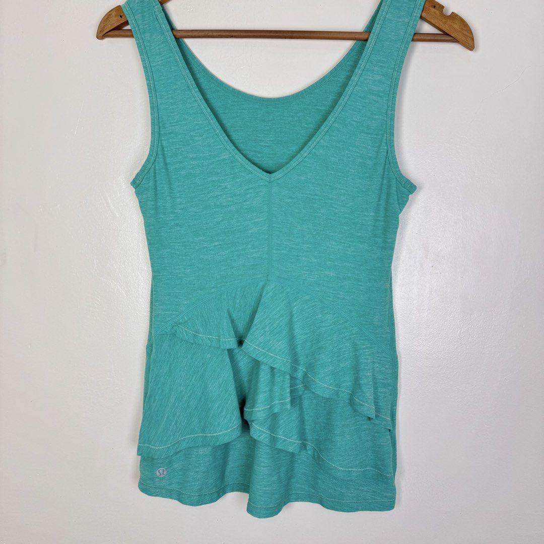 Lululemon Teal Ruffle Tank Top (Category: Activewear) located in Calasiao. Submitted by liascorner (Listing ID 1462601090, Image 3). Description: - Lululemon teal tank top - V-neck design - Cute tiered ruffle detail on the front - Heathered fabric texture - Versatile for workouts or casual wear - Features Lululemon logo on the hem.