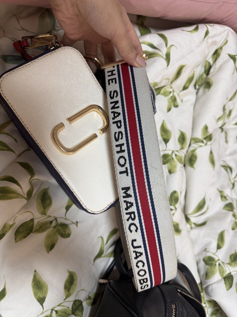 Marc Jacobs Snapshot Camera Bag White Red Blue Strap (Category: Luxury Bags & Wallets) located in Daraga. Submitted by kyotonara1010 (Listing ID 1462606072, Image 2). Description: - Authentic Marc Jacobs Snapshot Bag - Color: White Leather - Hardware: Gold - Includes signature striped strap - Red accent detail on the back - Zipper closure for secure storage - Ideal for everyday use -condition: good condition.