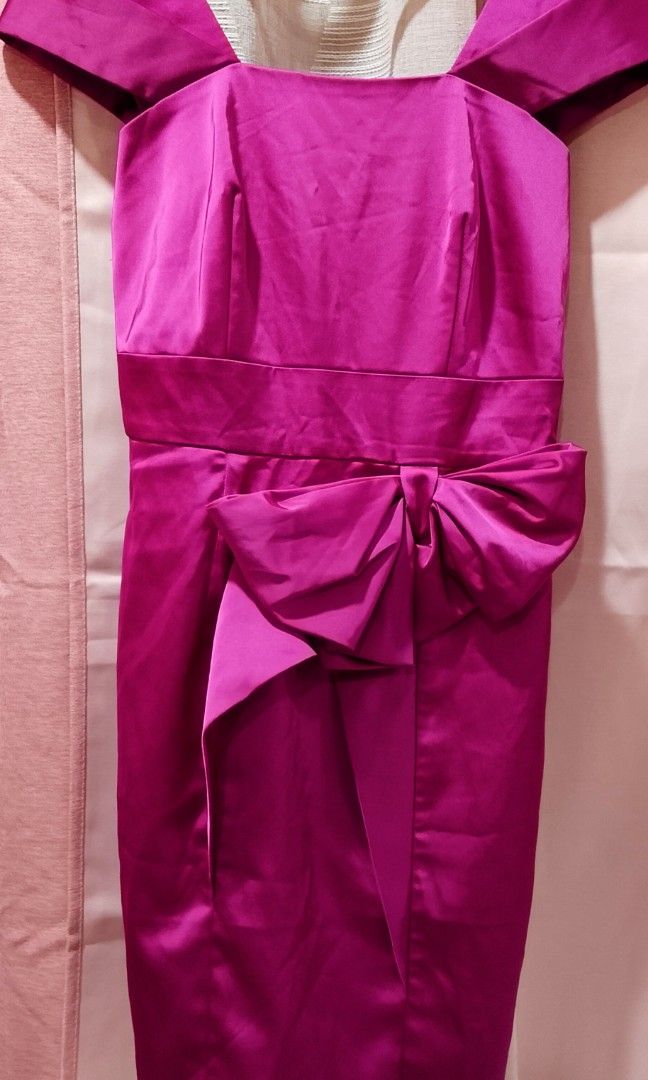 Fuschia cocktail dress (Category: Evening dresses & gowns) located in Cabanatuan. Submitted by miss.maia (Listing ID 1462662367, Image 1). Description: Cocktail Dress featured here in the fuchsia/magenta color option. It is a sheath-style cocktail dress crafted from sleek satin, characterized by its off-the-shoulder straps, a squared neckline, and a prominent structured waist bow.