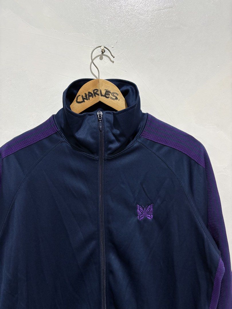 Needles Track Jacket Navy Purple Butterfly Logo Poly Smooth (Category: Coats, Jackets and Outerwear) located in Cabanatuan. Submitted by chingweyyy (Listing ID 1462619341, Image 2). Description: - Brand: Needles - Color: Navy Blue - Design: Purple stripe details on sleeves and shoulders - Logo: Embroidered butterfly on chest - Closure: Zipper - Pockets: Two front pockets - Size: L - Style: Great for casual wear - 24 Width x 28 Length.
