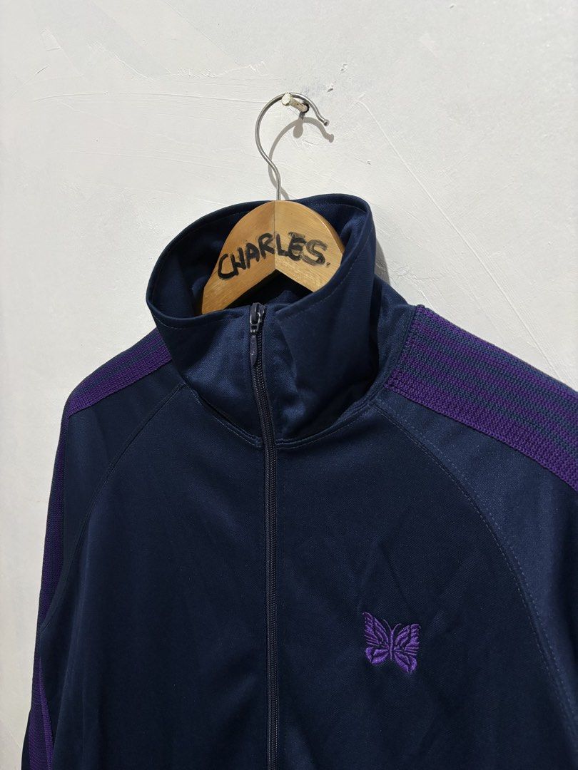 Needles Track Jacket Navy Purple Butterfly Logo Poly Smooth (Category: Coats, Jackets and Outerwear) located in Cabanatuan. Submitted by chingweyyy (Listing ID 1462619341, Image 3). Description: - Brand: Needles - Color: Navy Blue - Design: Purple stripe details on sleeves and shoulders - Logo: Embroidered butterfly on chest - Closure: Zipper - Pockets: Two front pockets - Size: L - Style: Great for casual wear - 24 Width x 28 Length.