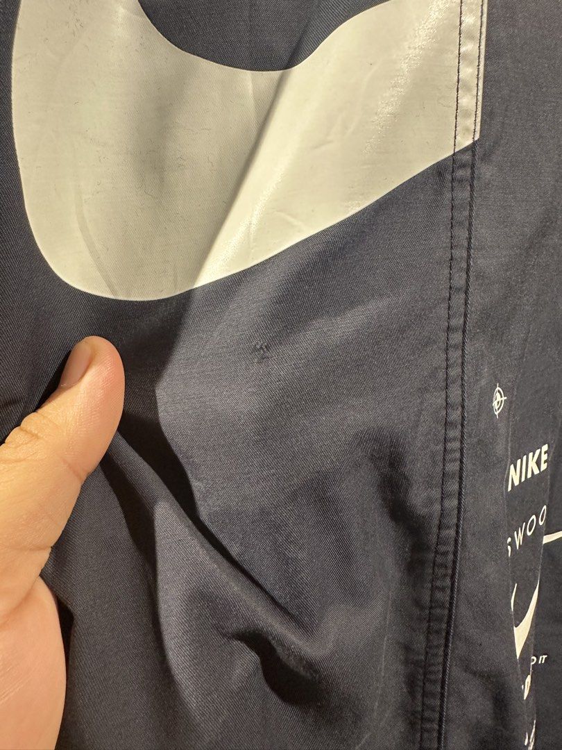 Nike Standard Fit Bomber Jacket (Category: Coats, Jackets and Outerwear) located in Manila. Submitted by gelo1999 (Listing ID 1462620868, Image 3). Description: - Navy blue Nike bomber jacket - Size: Medium (M) - Iconic Nike swoosh logo on the front - Large swoosh with text details on the back - Text graphics on the sleeve - Standard fit - Made in Vietnam - Note: Small mark on the front, as shown in the last photo..