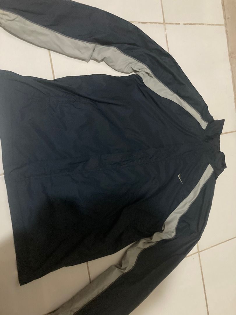 Nike Vintage 90s small logo windbreaker (Category: Coats, Jackets and Outerwear) located in Angono. Submitted by jc_ilagan (Listing ID 1462471954, Image 3). Description: - Classic Nike windbreaker jacket - Color: Navy blue with light grey accents on sleeves and sides - Material: Lightweight, perfect for layering or light rain protection - Features: Front pockets, drawstring at the bottom hem - Style: Versatile for casual wear or sports activities