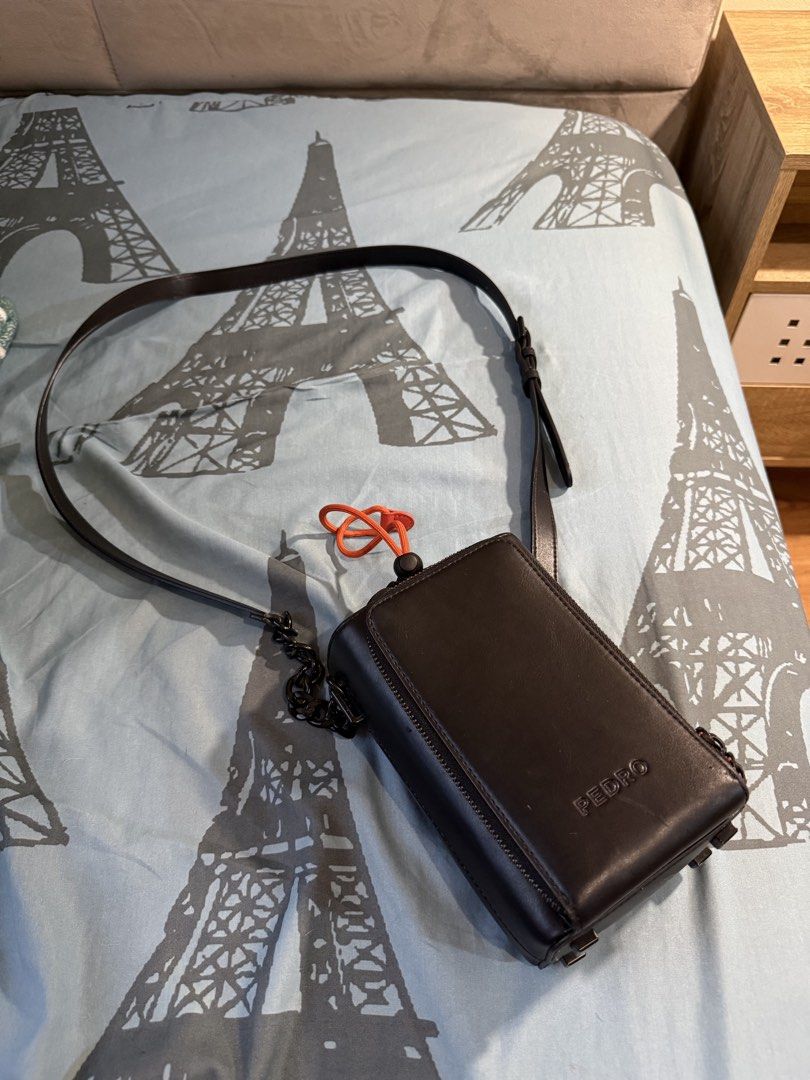 Pedro Sling Bag (Category: Sling Bags) located in Mandaluyong City. Submitted by jamesy006 (Listing ID 1462554915, Image 2). Description: - Brand: Pedro - Color: Black - Material: Leather - Features: Orange drawstring detail, front zip pocket - Straps: Long adjustable strap, chain detail on one side - Wearability: Crossbody or shoulder - Size: Ideal for essentials.