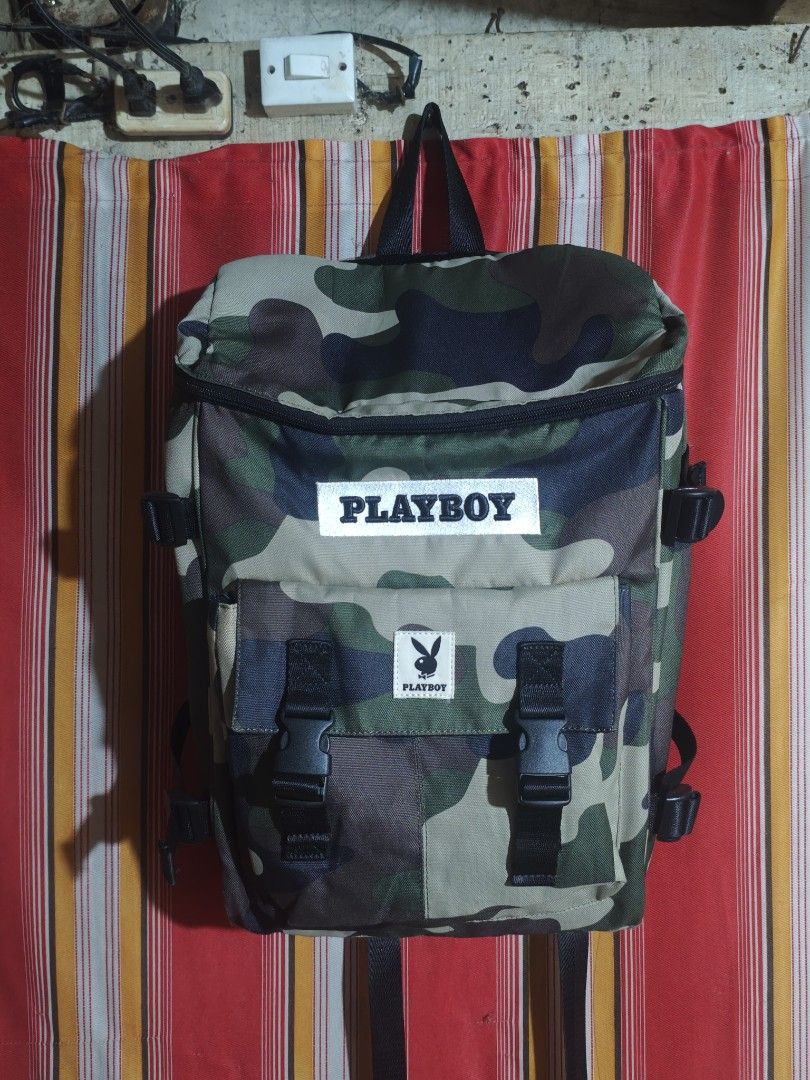 PLAYBOY Camo Backpack (Category: Backpacks) located in San Pedro. Submitted by streetthriftsph (Listing ID 1462571572, Image 1). Description: PLAYBOY Camo Backpack 1650 Shipped Condition: 9.5/10 Size: 14 width X 16.5 Length Compartments: 2 Zippers: 9.5/10 Working Straps: 9.5/10 Intact Colorate; 9.5/10 Print: 9.5/10 Embroidered logo and Cloth Patch.
