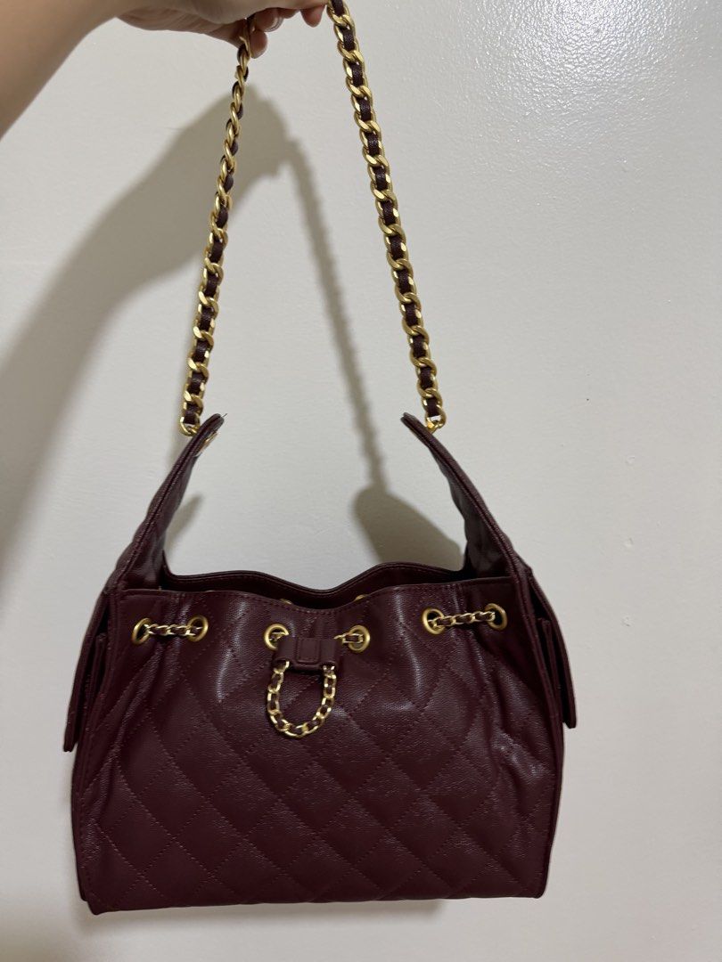 Quilted Drawstring Chain Shoulder Bag Burgundy (Category: Shoulder Bags) located in Marilao. Submitted by anp129 (Listing ID 1462452739, Image 2). Description: - Chic burgundy quilted handbag - Elegant gold chain strap - Secure drawstring closure - Convenient front flap pocket - Beautiful textured finish - Stylish gold hardware details - Versatile for everyday or evening wear.