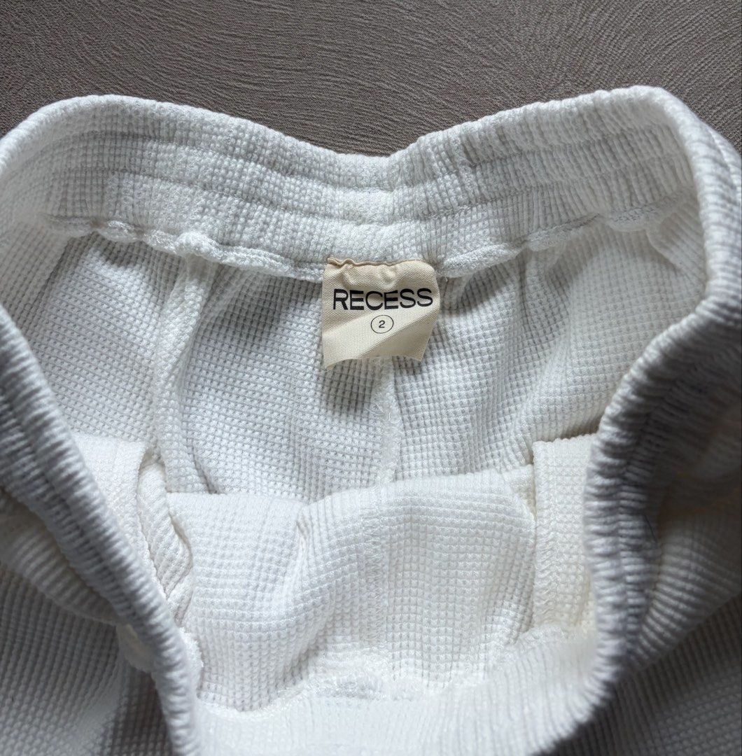 Recess White Waffle Knit Drawstring Shorts Size 2 (Category: Shorts) located in Muntinlupa City. Submitted by secondhandlove12345 (Listing ID 1462499307, Image 2). Description: - Brand: Recess - Style: White waffle knit shorts - Size: 2 - Features: Drawstring waist, contrasting rust-colored side stripes - Perfect for: Lounging, casual wear - Comfort: Comfortable and stylish.
