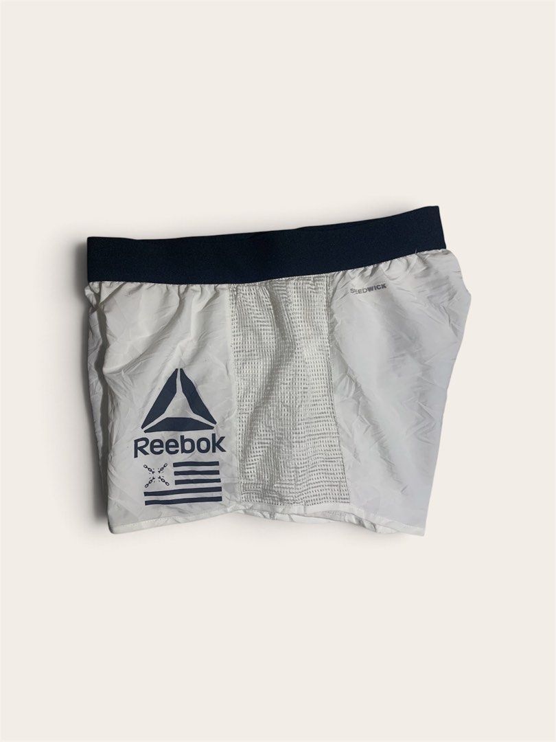 Reebok White Running Shorts with Mesh Panels (Category: Activewear) located in Davao. Submitted by youngboythrift25 (Listing ID 1462610107, Image 1). Description: - White Reebok running shorts - Dark blue waistband - Side mesh panels for enhanced breathability - Reebok logo and graphic print on the front - Lightweight material, ideal for workouts or casual wear - Elastic waistband for a comfortable and secure fit.
