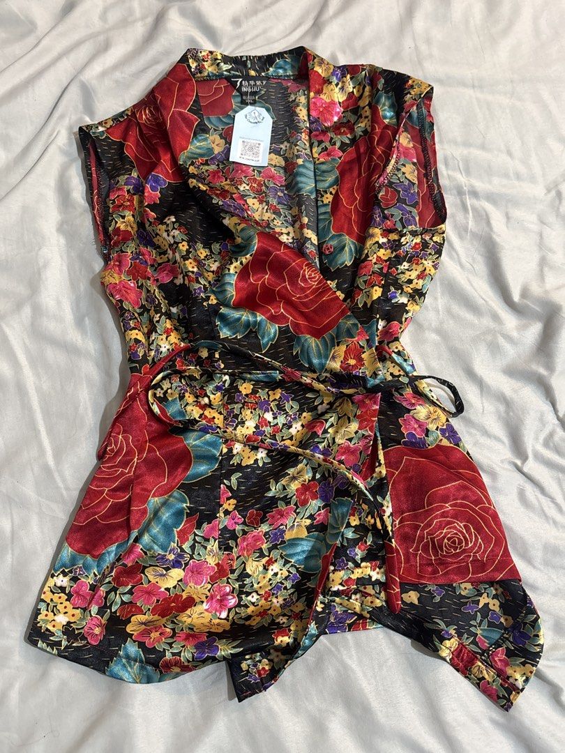 Chinese Floral Top (Category: Sleeveless) located in Manila. Submitted by shihtzuluvr (Listing ID 1462540109, Image 1). Description: - Vibrant satin wrap top - Size Small to Medium - Features large red roses and colorful flowers on a black background - Includes a tie belt for a secure fit - Sleeveless design RFS: decluttering MOP: Gcash / Maya MOD: Lalamove / LBC.