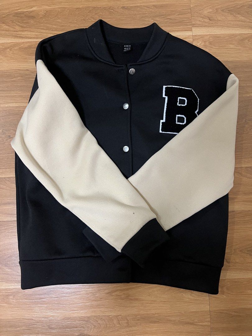 SHEIN Black & Beige Varsity Letterman Jacket (Category: Coats, Jackets and Outerwear) located in San Fernando. Submitted by nathan_pasahol (Listing ID 1462594559, Image 1). Description: - Black varsity jacket with beige sleeves - Features a large white 'B' patch on the chest - Button-up front closure - Ribbed collar, cuffs, and hem for a snug fit - Ideal for a casual, sporty aesthetic - Versatile: pairs well with jeans or leggings.