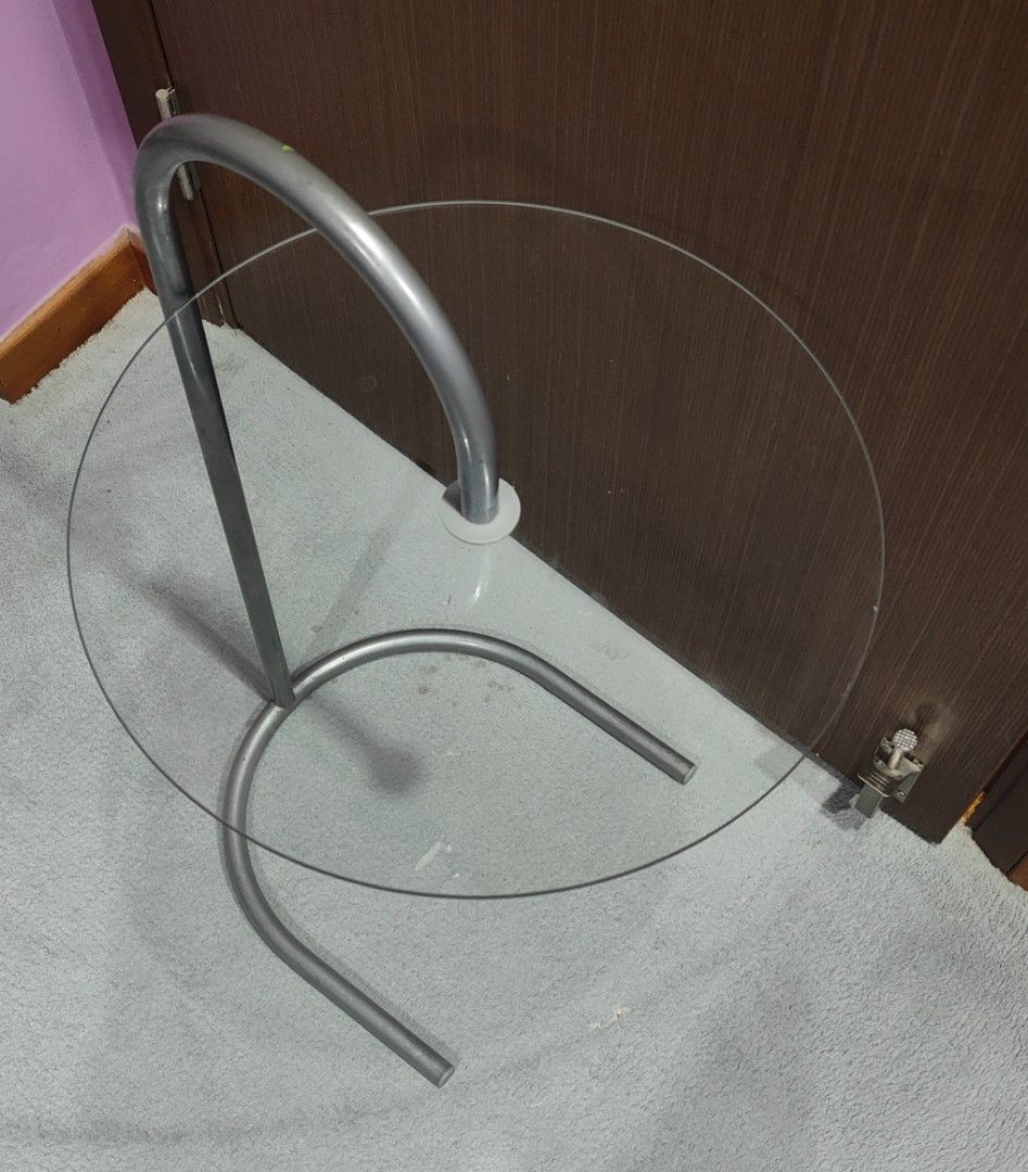 Side table (Category: Tables & Sets) located in Singapore. Submitted by cookie1881 (Listing ID 1462649390, Image 3). Description: - Modern side table with a unique curved design. - Features a clear glass tabletop. - Sturdy silver metal frame. - Dimensions: Diameter 16 inches, Height 21 inches. - Ideal for living rooms, bedrooms, or as an accent piece. - 2 units at $10 each. .