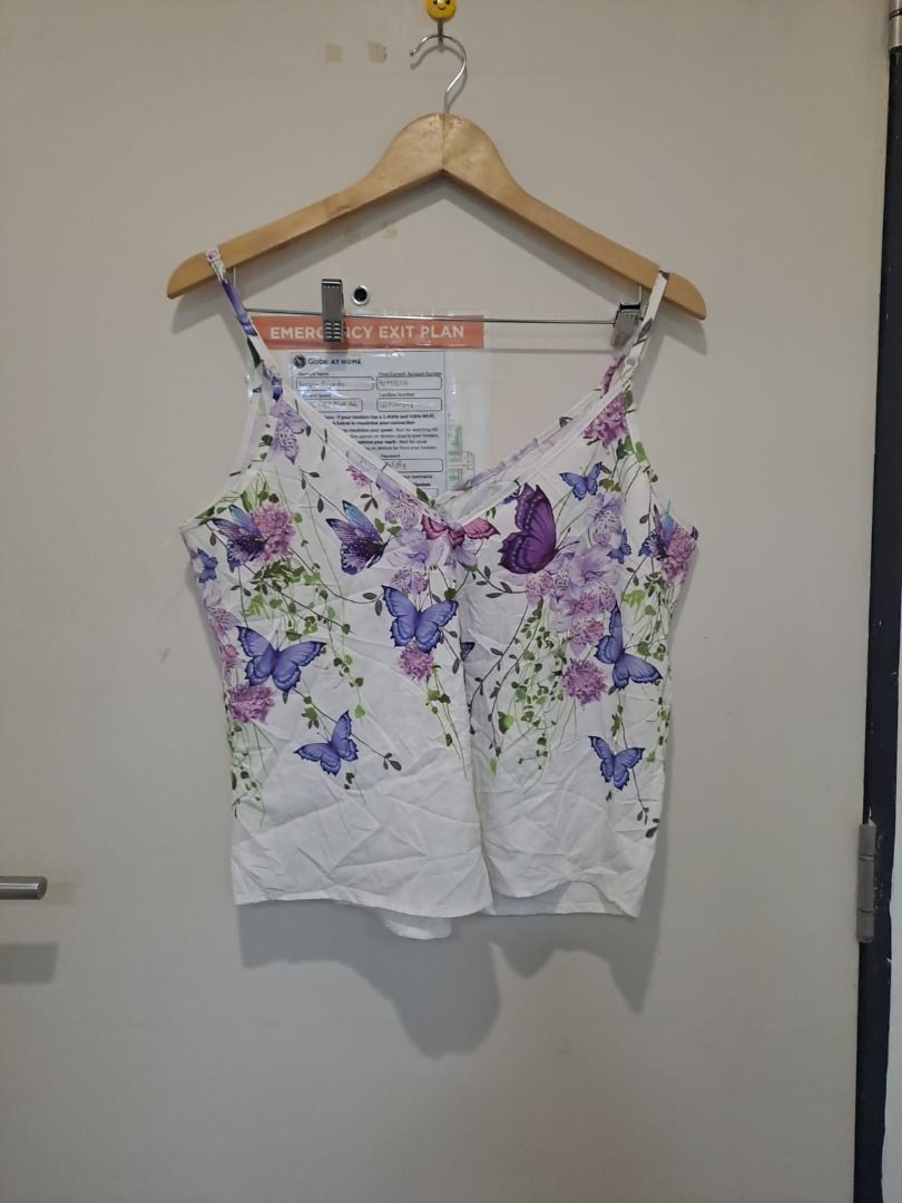 sleeveless top with butterflies design (Category: Sleeveless) located in Mandaluyong City. Submitted by epicowl-c93c (Listing ID 1462586400, Image 2). Description: This is a women's V-neck camisole top featuring a vibrant purple butterfly and floral print on a clean white background. It is designed with thin spaghetti straps,.