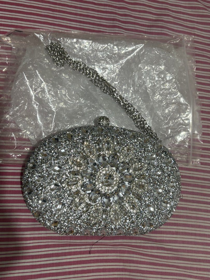 Sparkly Rhinestone Clutch Bag with Chain Strap (Category: Clutches) located in Manila. Submitted by nykji96 (Listing ID 1462536208, Image 1). Description: - Dazzling oval clutch bag covered in rhinestones. - Features a detachable silver chain strap for versatile wear. - Luxurious satin lining inside. - Secure clasp closure at the top. - Ideal for parties, weddings, and special occasions. - Dimensions: Approximately 8 inches wide and 5 inches tall