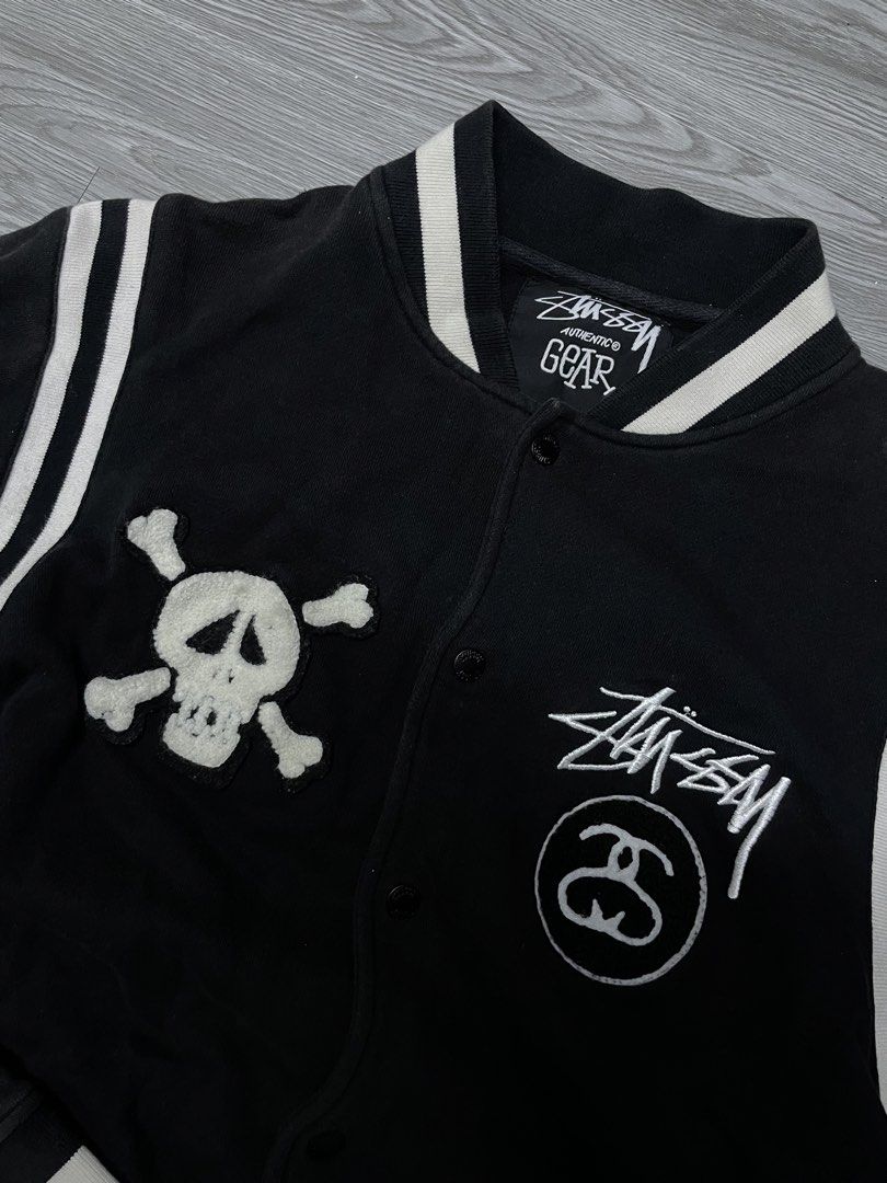 Stussy Skull & Crossbones Varsity Jacket (Category: Coats, Jackets and Outerwear) located in Manila. Submitted by yourfavoriteplug (Listing ID 1462507685, Image 2). Description: - Classic Black Stussy Varsity Jacket - White striped sleeves and collar for a retro look - Unique skull and crossbones patch on left chest - Prominent Stussy logos on right chest and back - Easy button-up closure - Size Large (L).