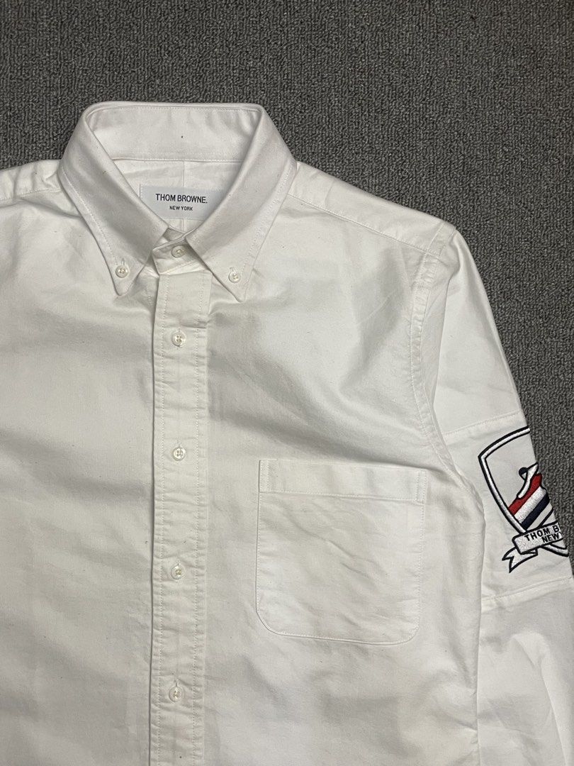Thom Browne New York White Button-Down Shirt with Patch (Category: Tshirts & Polo Shirts ) located in Quezon City. Submitted by cozy_thrifting (Listing ID 1462595234, Image 2). Description: - Classic white button-down shirt - Brand: Thom Browne - Signature sleeve patch detail - Button collar - Chest pocket - Tagged size: 1 - Ideal for smart casual outfits 18.5 Width 28 Length 23.5 Sleeves .