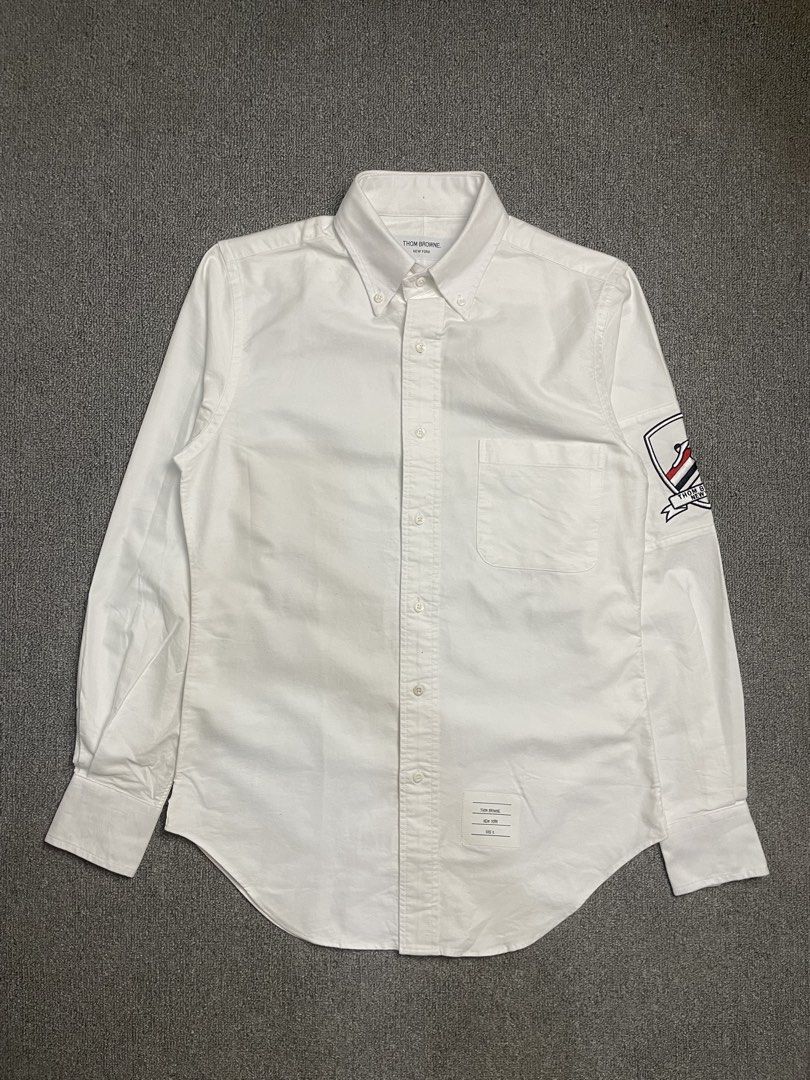 Thom Browne New York White Button-Down Shirt with Patch (Category: Tshirts & Polo Shirts ) located in Quezon City. Submitted by cozy_thrifting (Listing ID 1462595234, Image 1). Description: - Classic white button-down shirt - Brand: Thom Browne - Signature sleeve patch detail - Button collar - Chest pocket - Tagged size: 1 - Ideal for smart casual outfits 18.5 Width 28 Length 23.5 Sleeves .