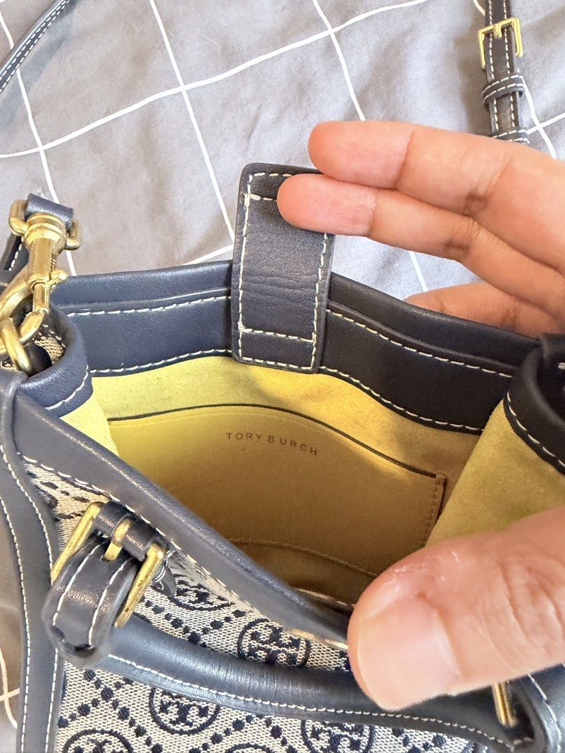 Tory Burch Monogram Tote Bag Navy Blue (Category: Luxury Bags & Wallets) located in Makati City. Submitted by purewind.a22dcd (Listing ID 1462528771, Image 3). Description: - Navy blue Tory Burch tote bag - Classic monogram pattern - Top handles - Detachable crossbody strap - Bright yellow interior lining - Interior slip pocket - Gold hardware details - Ideal for everyday use.