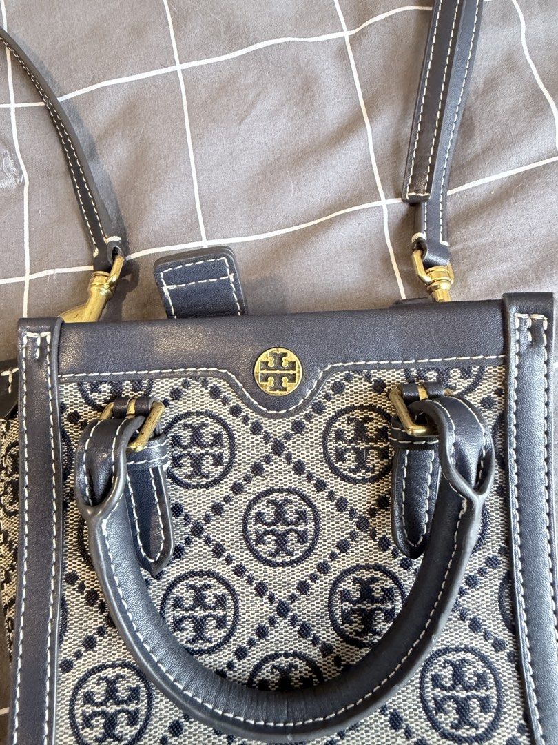 Tory Burch Monogram Tote Bag Navy Blue (Category: Luxury Bags & Wallets) located in Makati City. Submitted by purewind.a22dcd (Listing ID 1462528771, Image 2). Description: - Navy blue Tory Burch tote bag - Classic monogram pattern - Top handles - Detachable crossbody strap - Bright yellow interior lining - Interior slip pocket - Gold hardware details - Ideal for everyday use.