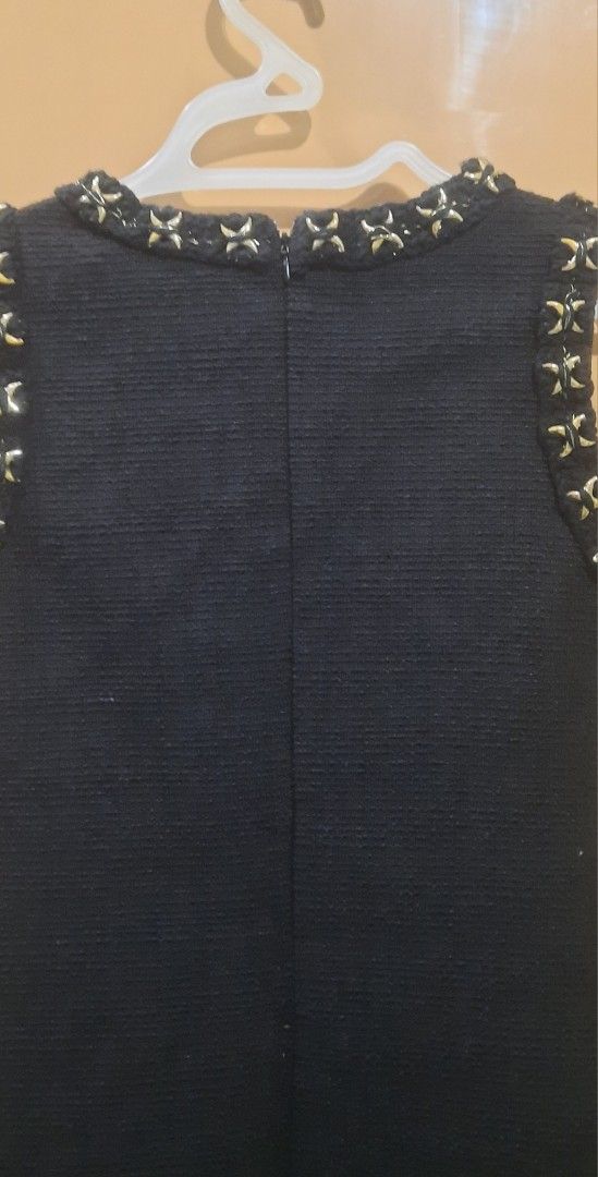 Tweed black dress (Category: Babies & Kids Fashion) located in Pasig City. Submitted by tjrtforeve46982 (Listing ID 1462615366, Image 3). Description: Black sleeveless dress. V-neckline with gold stud details. Similar embellishments on the shoulders and hem. Zipper closure at the back. Textured fabric. Knee-length cut..