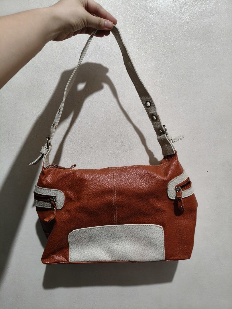 Vintage Leather Shoulder Bag (Category: Shoulder Bags) located in Quezon City. Submitted by giveitalife (Listing ID 1462447505, Image 2). Description: - Cute orange and white shoulder bag - Textured leather material - Front zippered pockets - Main compartment with zipper closure - Interior zippered pocket and slip pocket - Adjustable buckle strap - Minor wear on strap attachment points.