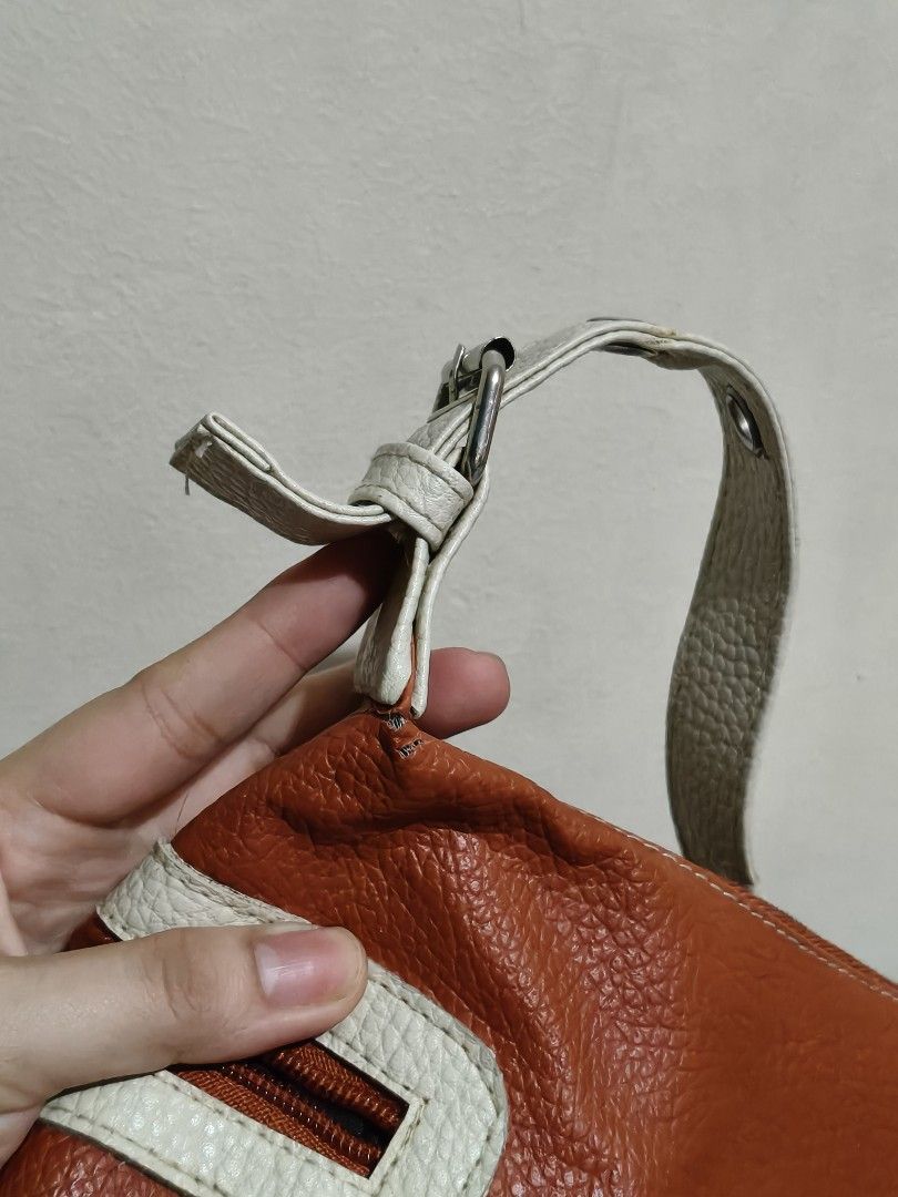 Vintage Leather Shoulder Bag (Category: Shoulder Bags) located in Quezon City. Submitted by giveitalife (Listing ID 1462447505, Image 3). Description: - Cute orange and white shoulder bag - Textured leather material - Front zippered pockets - Main compartment with zipper closure - Interior zippered pocket and slip pocket - Adjustable buckle strap - Minor wear on strap attachment points.