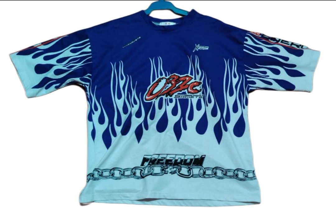032c K.M Studios Flame Graphic T-shirt (Category: Tshirts & Polo Shirts ) located in Abucay. Submitted by fnds_wr (Listing ID 1462829044, Image 1). Description: - Brand: K.M Studios - Design: Blue and white flame graphic - Text: 'OBZC SOCIETE' and 'FREEDOM' - Accent: Chain graphic at the bottom - Size: 03 - Style: Casual wear.