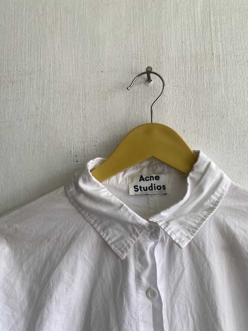 Acne Studios White Cotton Button-Up Shirt (Category: Tshirts & Polo Shirts ) located in Manila. Submitted by anthony1723 (Listing ID 1462716447, Image 2). Description: - Classic white button-up shirt from Acne Studios - Made from 100% premium cotton - Features a relaxed fit and stylish curved hem - Perfect for versatile styling – wear it alone or layer it up - A must-have staple for any wardrobe.
