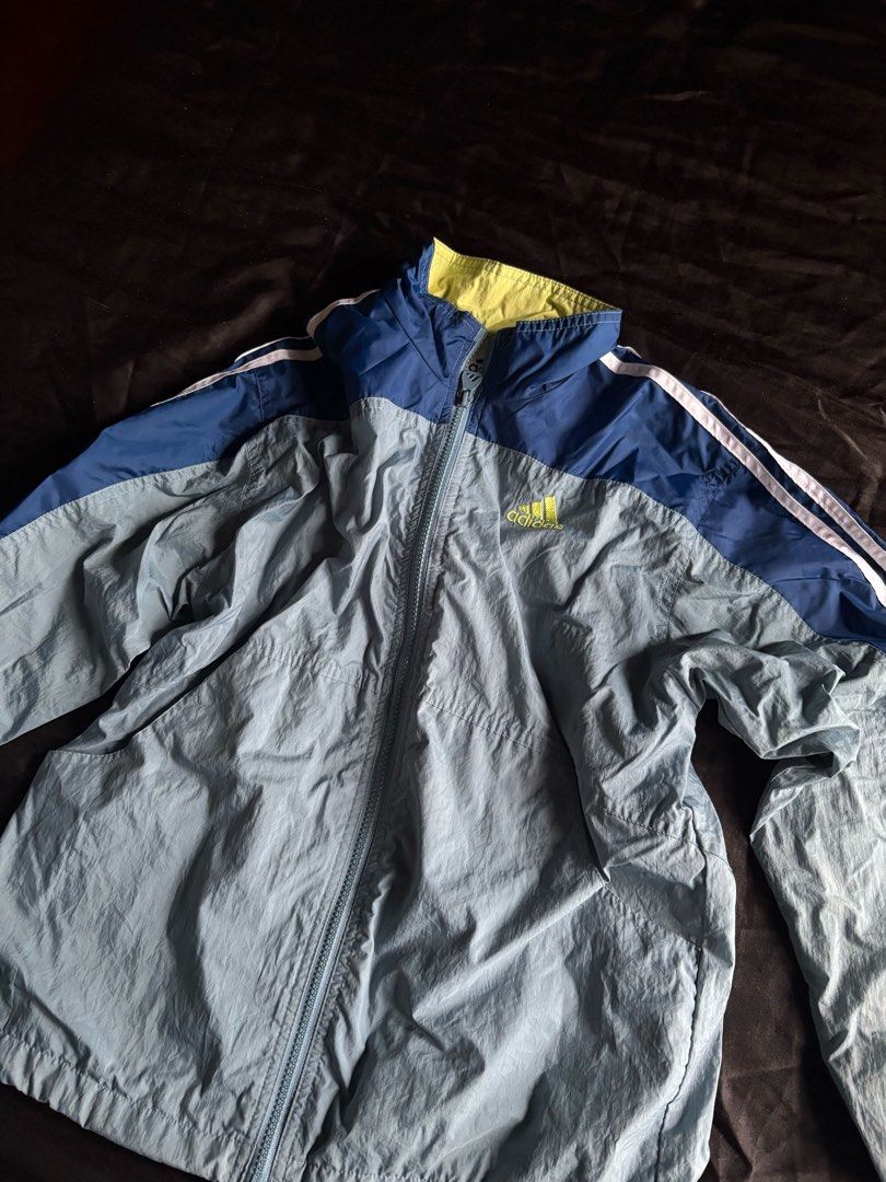 Adidas Windbreaker Jacket Blue Grey White Stripes (Category: Coats, Jackets and Outerwear) located in Calamba. Submitted by leeadriannn796 (Listing ID 1462696953, Image 3). Description: - Lightweight Adidas jacket - Blue and grey color blocking with white sleeve stripes - Zip-up front with a hood - Ideal for casual wear or sports - Made in Malaysia - Shell: 100% Nylon - Lining: 100% Polyester.