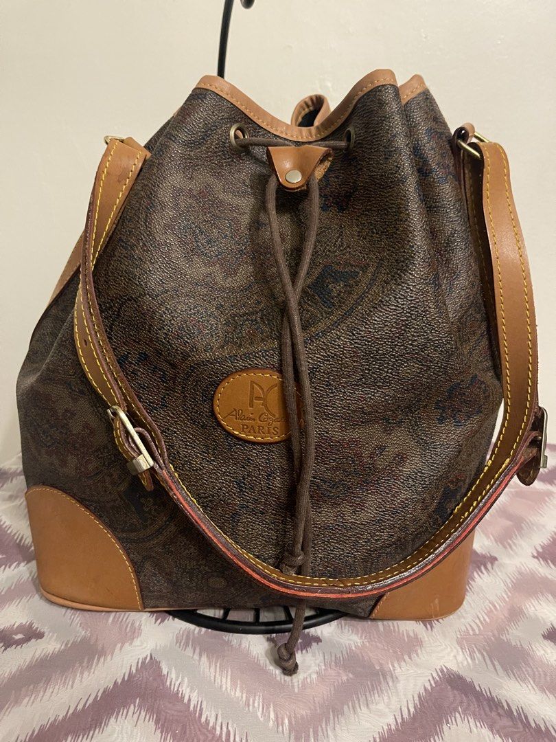 Alain Gilardi Paris Monogram Bucket Bag (Category: Luxury Bags & Wallets) located in General Trias. Submitted by laconchita_tesoros (Listing ID 1462728414, Image 1). Description: - Vintage Alain Gilardi Paris bucket bag - Classic monogram print - Tan leather trim and strap - Secure drawstring closure - Perfect size for everyday essentials - Stylish Parisian accessory.