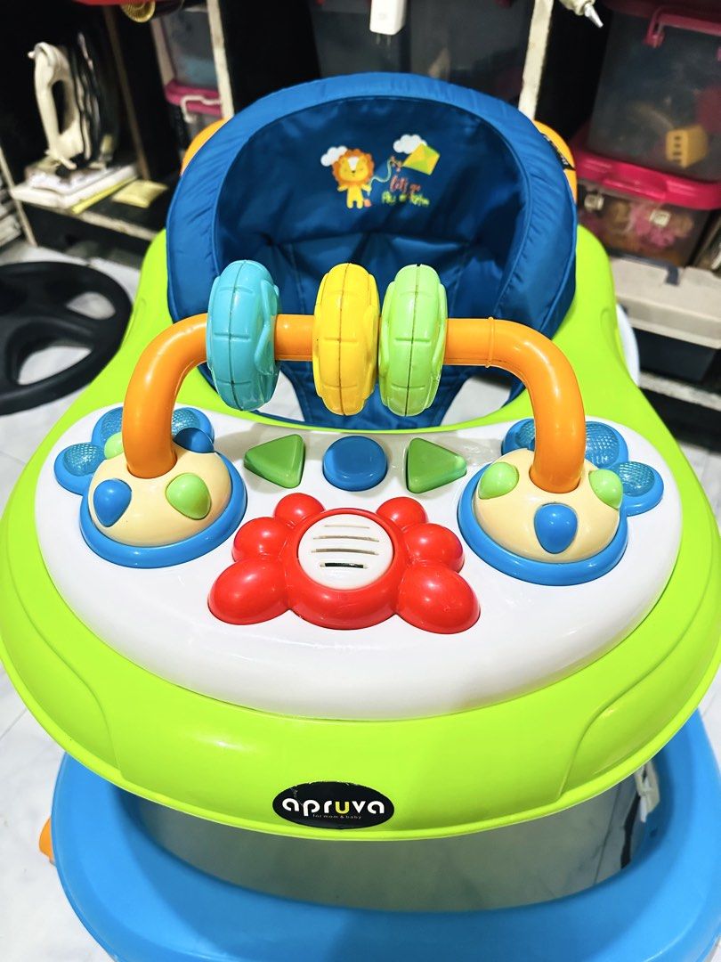 Apruva Baby Walker with Toys (Category: Infant Playtime) located in Manila. Submitted by allysa023025488 (Listing ID 1462820768, Image 2). Description: Aprica baby walker in green and blue. Has a toy bar with spinning rings and buttons. Seat is blue with a lion print. Some wear and tear on the metal legs, as shown in photos. Still functional for little ones learning to walk..