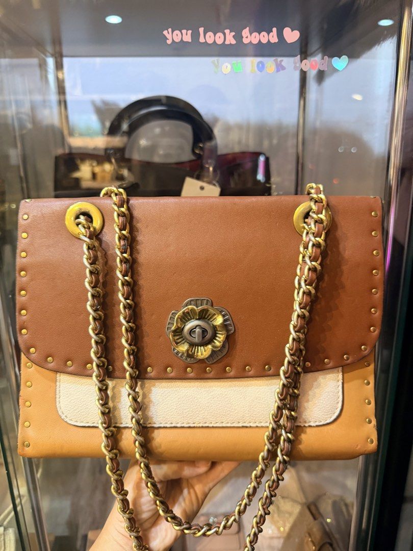 Authentic Coach Brown Leather Studded Chain Shoulder Bag (Category: Luxury Bags & Wallets) located in Dumaguete. Submitted by lovebags.ph (Listing ID 1462825780, Image 1). Description: - Stylish brown and cream leather shoulder bag - Elegant gold chain strap - Eye-catching studded details all around - Unique flower clasp closure - Practical interior with multiple compartments - Versatile for everyday wear or evening events.