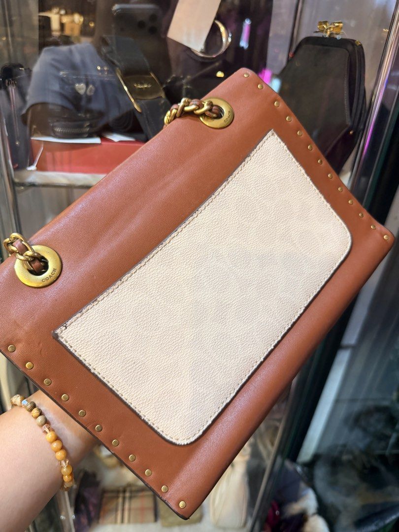 Authentic Coach Brown Leather Studded Chain Shoulder Bag (Category: Luxury Bags & Wallets) located in Dumaguete. Submitted by lovebags.ph (Listing ID 1462825780, Image 3). Description: - Stylish brown and cream leather shoulder bag - Elegant gold chain strap - Eye-catching studded details all around - Unique flower clasp closure - Practical interior with multiple compartments - Versatile for everyday wear or evening events.