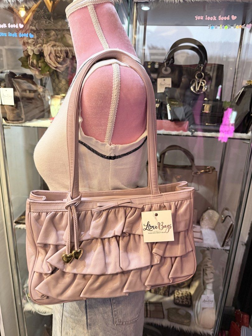 Authentic Lovcat Pink Ruffle Leather Shoulder Bag (Category: Shoulder Bags) located in Dumaguete. Submitted by lovebags.ph (Listing ID 1462827775, Image 2). Description: - Adorable pink shoulder bag from LoveBags. - Made of soft leather with charming ruffle details. - Features two small heart charms on the front tie. - Comfortable shoulder straps. - Ideal size for carrying your essentials. - Comes with the original tag..