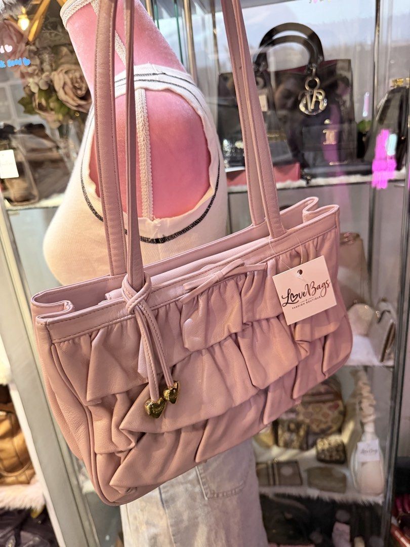 Authentic Lovcat Pink Ruffle Leather Shoulder Bag (Category: Shoulder Bags) located in Dumaguete. Submitted by lovebags.ph (Listing ID 1462827775, Image 1). Description: - Adorable pink shoulder bag from LoveBags. - Made of soft leather with charming ruffle details. - Features two small heart charms on the front tie. - Comfortable shoulder straps. - Ideal size for carrying your essentials. - Comes with the original tag..