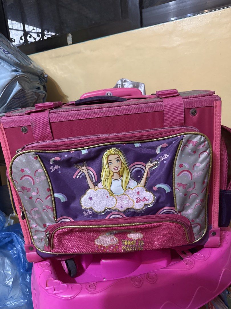 Barbie Rolling Backpack with Wheels and Handle (Category: Backpacks) located in Manila. Submitted by zealbear_602543 (Listing ID 1462790190, Image 3). Description: - Adorable pink Barbie rolling backpack - Features a fun rainbow and cloud design - Includes a front zipper pocket with a Barbie graphic - Easy to transport with retractable handle and wheels - Perfect for school or travel - Shows some signs of wear, but remains fully functional - Need